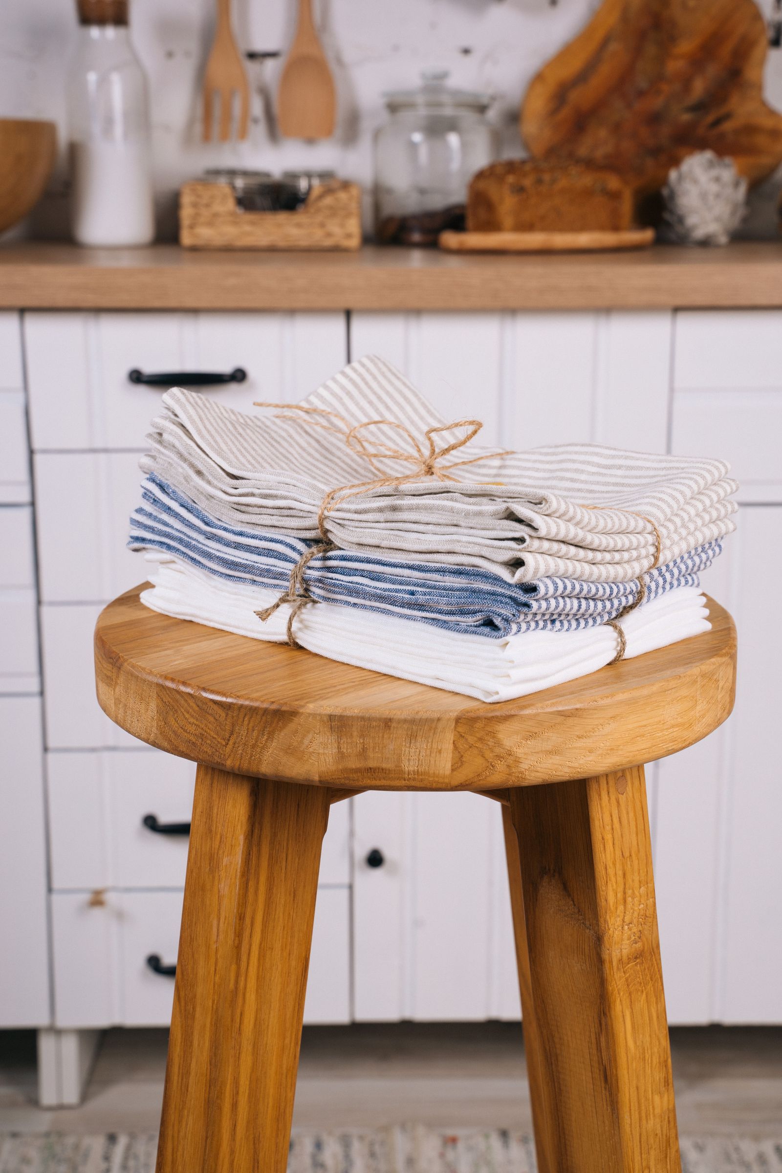 Stack of folded striped linen kitchen towels on a wooden stool in a kitchen