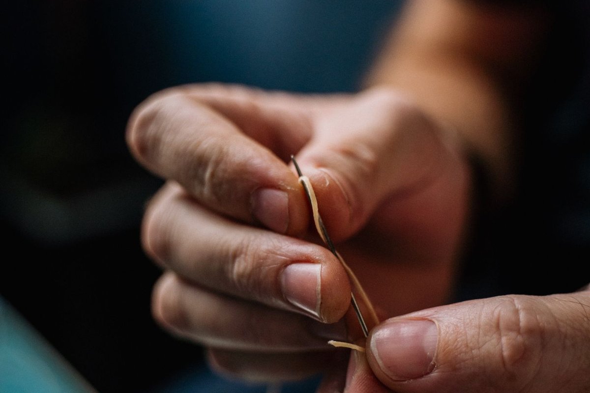 Close-up of two hands threading a sewing needle